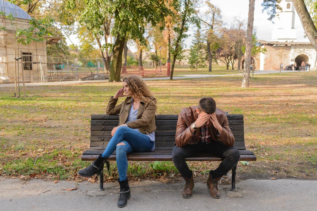 man and woman on a bench looking upset