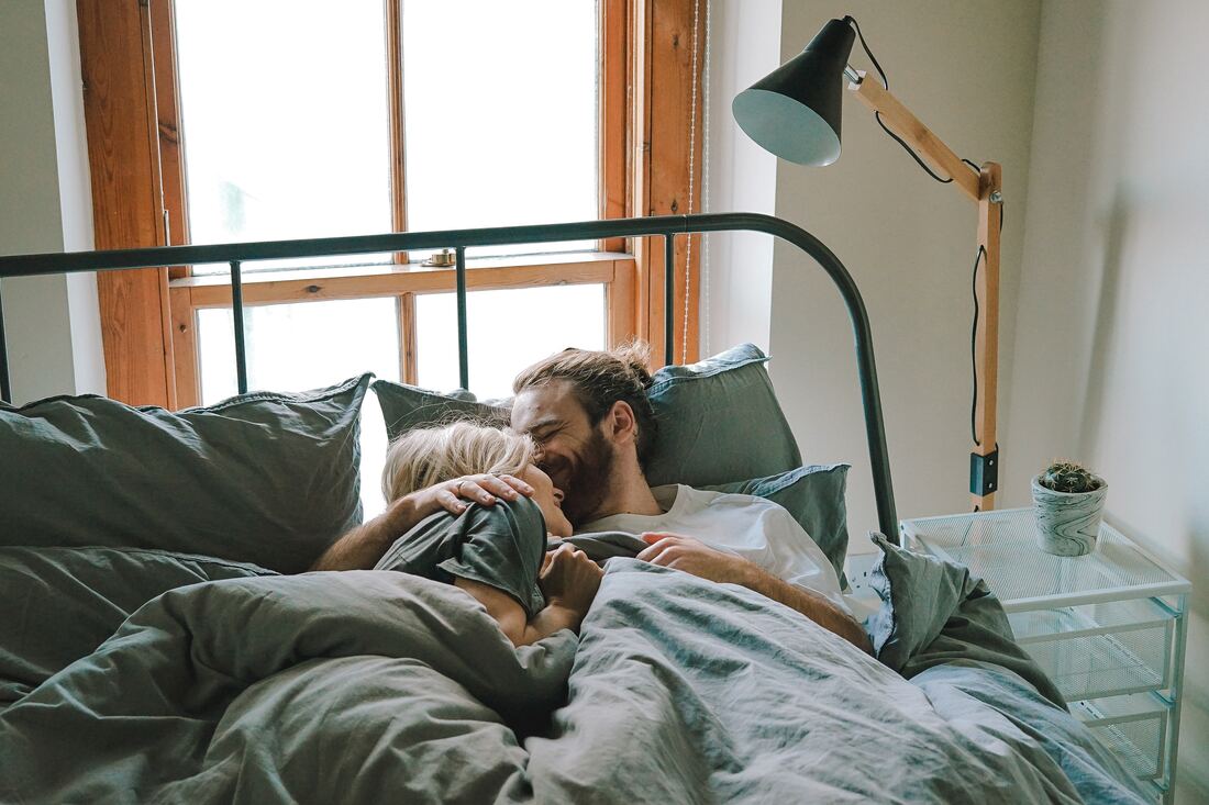 man and woman cuddling in bed